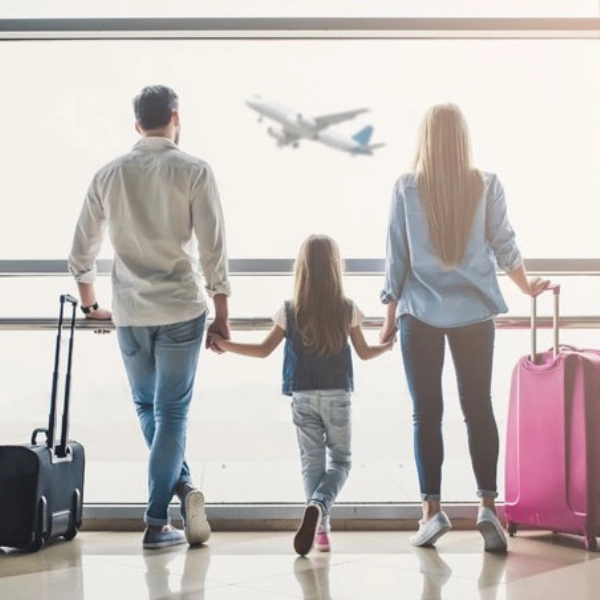 Seguro de Viajes - Familia mirando por la ventana de una terminal como despega un avión